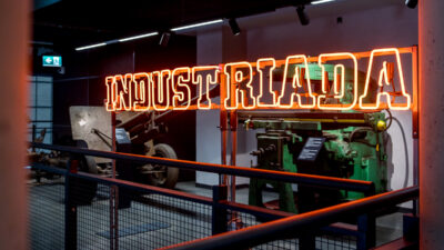 Neon z napisem "Industriada" na tle maszyn przemysłowych